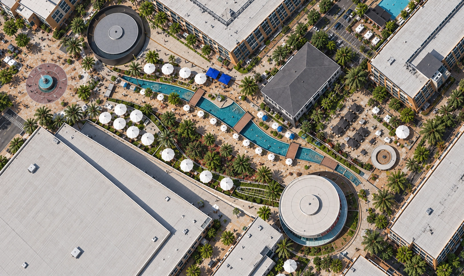 Aerial view of the Plaza: Toyota Arena to the south-west, the round venues, the water feature and the patios, with people moving in from every side toward the Plaza.